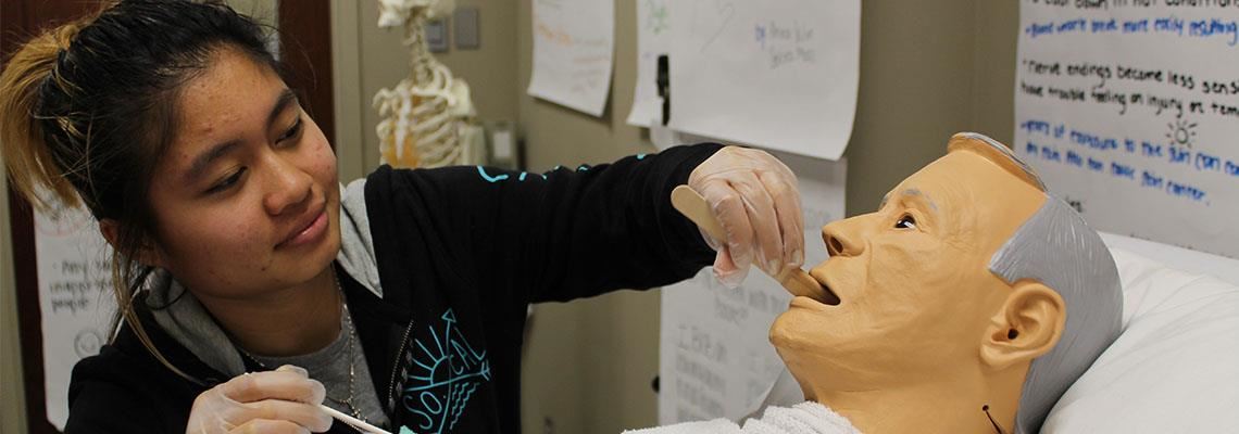 A student practices on a medical dummy